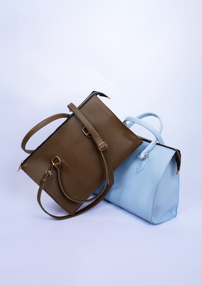 Two elegant leather bags in brown and blue displayed on a clean white background in a studio setting.